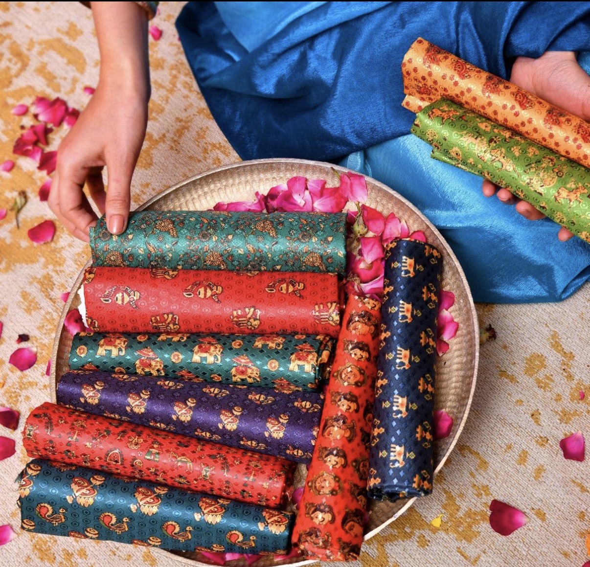A selection of richly coloured traditional silk-style textiles arranged on a tray